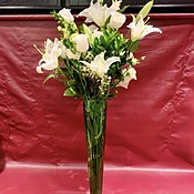 Custom arrangement of Casablanca lilies, white roses, white lisianthus & greens in clear glass vase